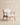 Wooden armchair with white bouclé upholstery and angled exposed wood frame, natural light wood finish — handcrafted accent chair made in India.