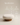 Round upholstered cream pouf with cylindrical wooden base, walnut wood finish — handcrafted accent ottoman made in India.
