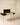 Black wooden writing desk with raised back panel, side drawer storage and natural wood tapered legs — handcrafted study table made in India.