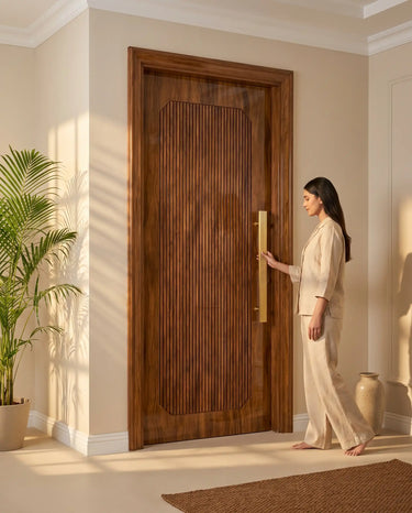 Luxury residential entrance featuring a premium solid wood main door with recessed vertical slatted panel, walnut finish and elegant brass pull handle in a modern home interior